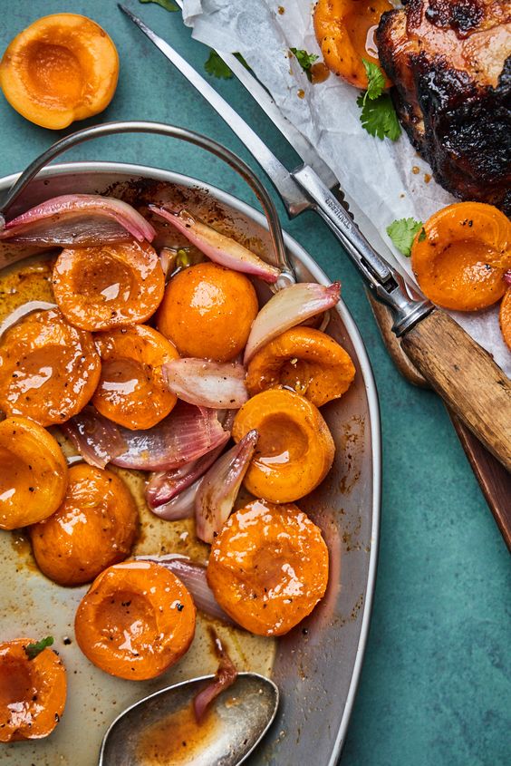 a pan of cooked apricots and onions sit next to s piece of chicken off to the side
