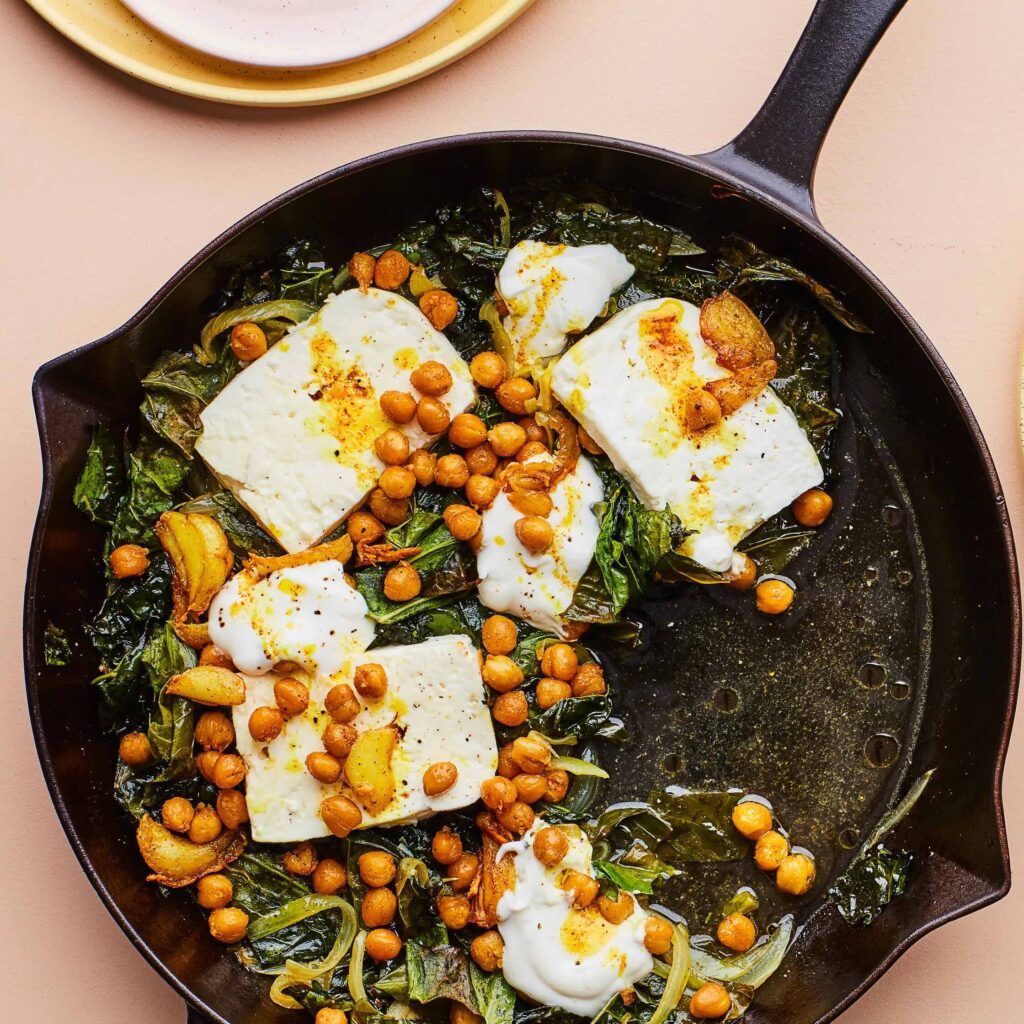 greens, chickpeas, and slices of feta in a cast iron skillet 