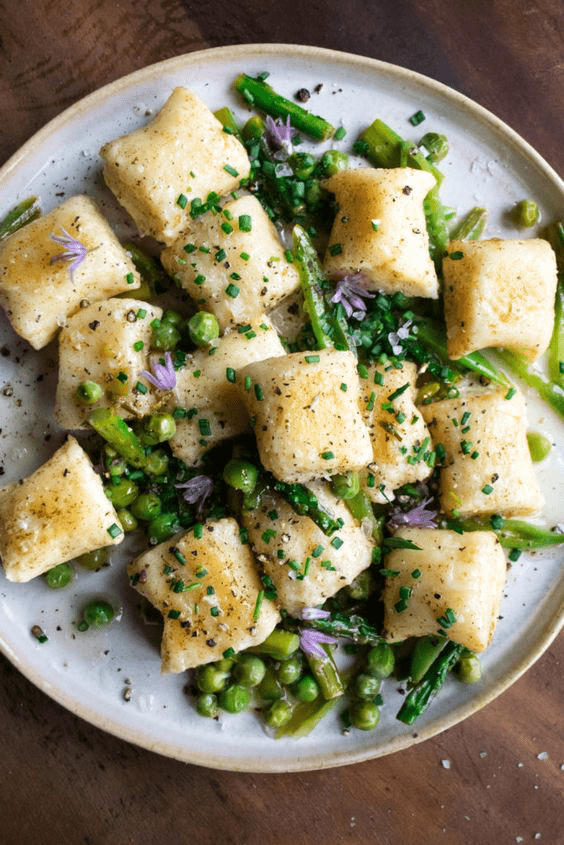 peas, asparagus, and pieces of gnocchi on a plate 