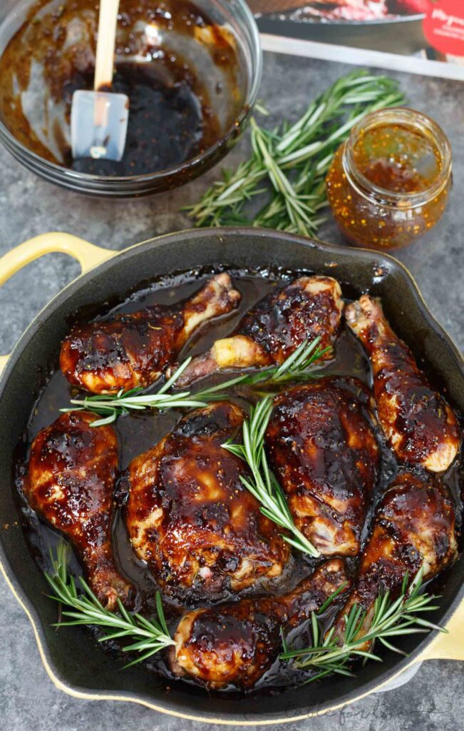 chicken with brown sauce and sprigs of rosemary in a dutch oven